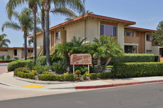 Front view of a multi-story condominium building with balconies and landscaping.