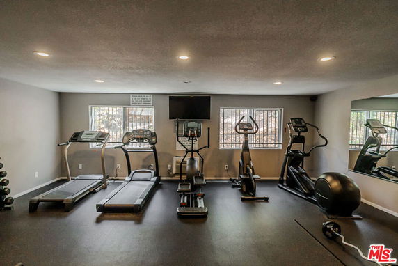 Indoor gym area with exercise machines including treadmills and elliptical trainers.