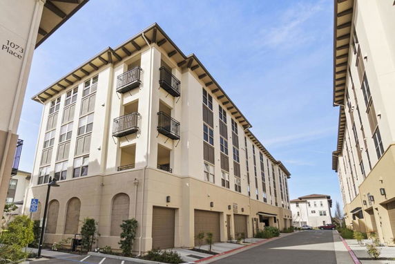 Front view of a multi-story building with balconies and garages.