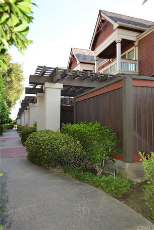 Side view of a residential building with a covered walkway and shrubs.