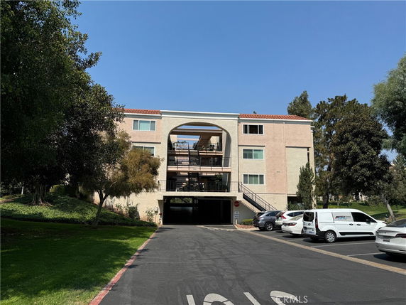 Front view of a multi-story apartment building with parking underneath.