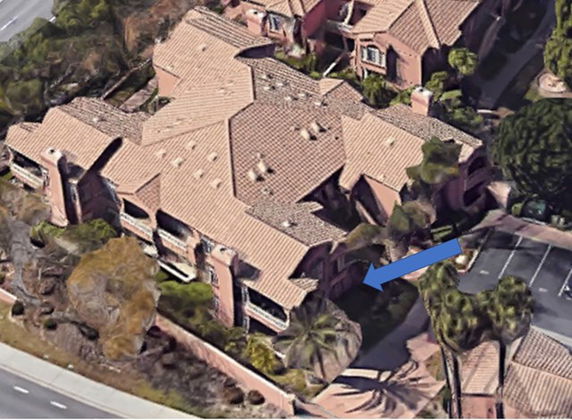 Aerial view of a multi-unit building with tiled roofs and surrounding greenery.
