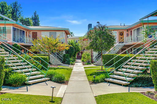 Front view of an apartment complex with multiple units and staircases leading to the entrances.