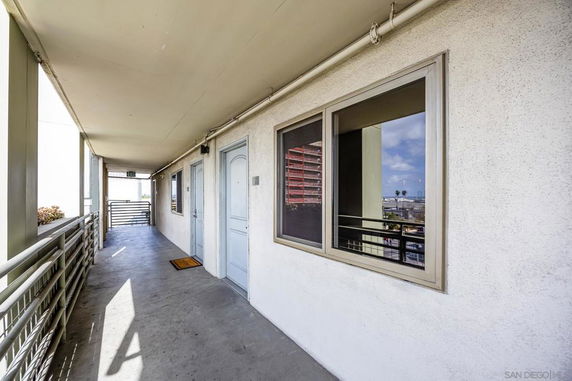 Exterior corridor of a building with railing and doors.