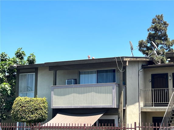 Front view of a two-story building with a balcony and satellite dish.