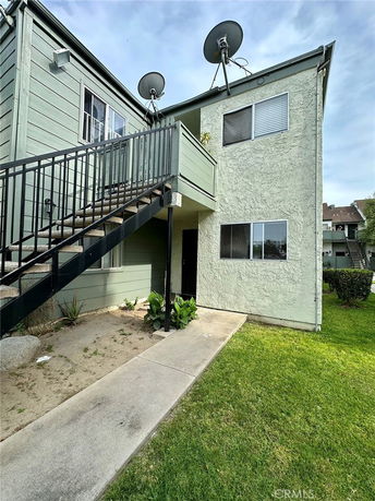 Front view of a two-story building with external staircase and satellite dishes on the roof.