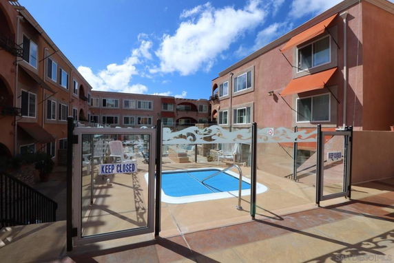 Outdoor view of a building complex with a swimming pool and safety gate.