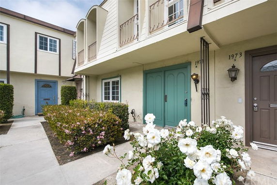Front view of a two-story townhouse with balconies and a green front door.