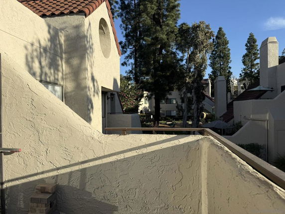 View of multi-story residential buildings with beige stucco walls and red tile roofs.