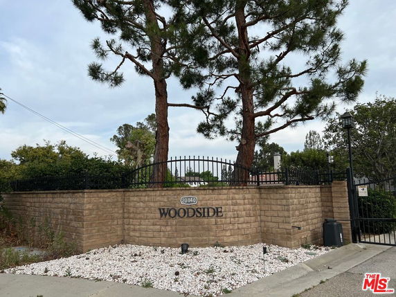 Front view of a stone wall with 'Woodside' sign and gate.