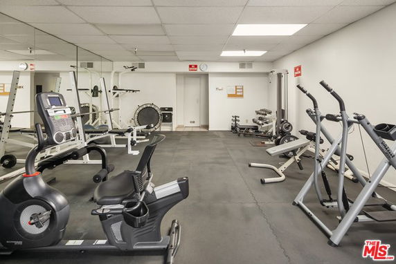 Indoor gym area with various exercise equipment and mirrored walls.
