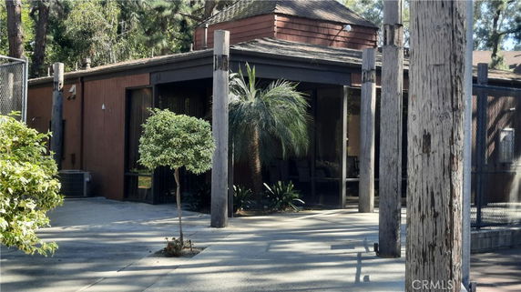 Front view of a single-story house with wood elements and surrounding plants.