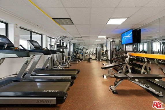 Indoor gym area with various exercise equipment, including treadmills, weights, and benches.