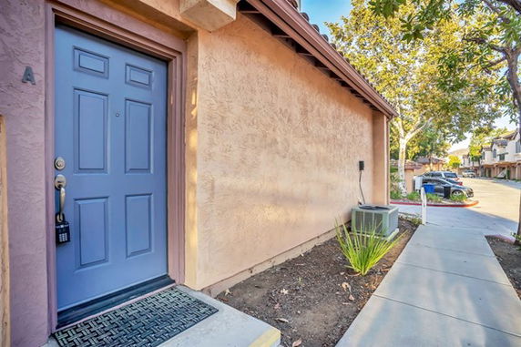 Front view of a single-story house with a blue door and stucco exterior.