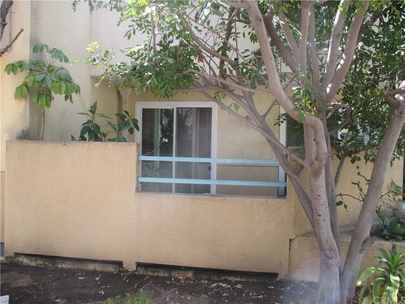 Front view of a house with a small balcony and tree in front