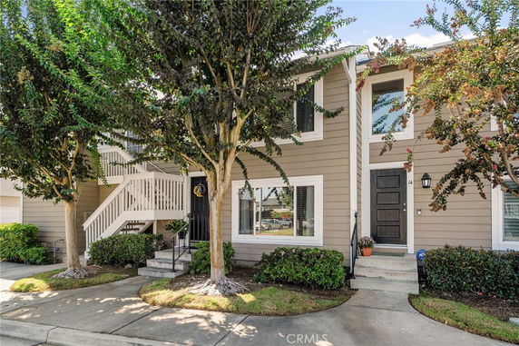 Front view of a two-story townhouse with a staircase leading to the entrance.
