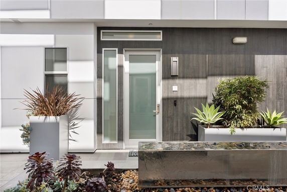 Front view of a modern house entrance with large glass door and potted plants.