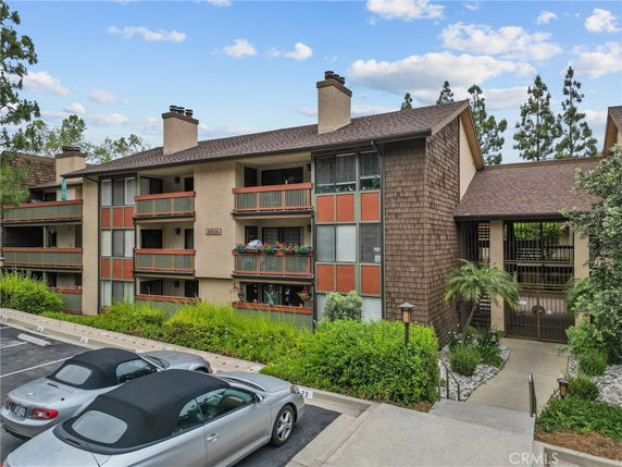 Front view of a multi-story residential building with balconies and a shingled roof.