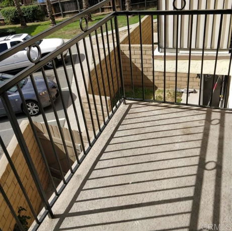 Balcony view showing outdoor parking area and nearby building structure.
