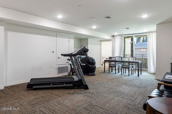 Indoor area featuring a treadmill and dining table with chairs.