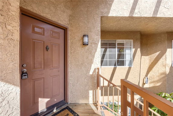 Front view of a house entrance with a brown door and a window adjacent to it.