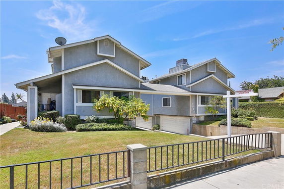 Front view of a multi-story house with a garage and a satellite dish on the roof.
