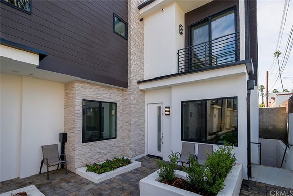 Front view of a modern two-story house with large windows and a small patio.