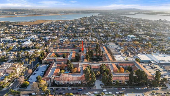 Aerial view of a neighborhood with buildings and water bodies in the background.