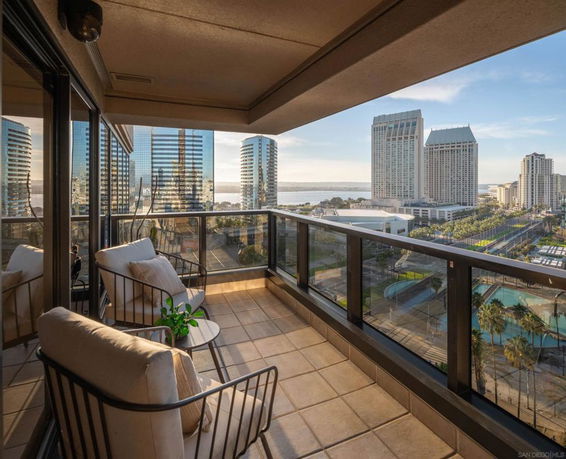 Panoramic view from a balcony overlooking a cityscape with tall buildings and a body of water in the background.
