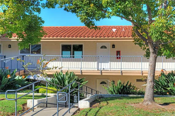 Front view of a two-story building with a red-tiled roof and a railing near the entrance.
