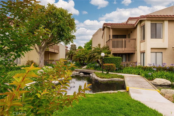 Front view of a multi-story building with balconies and landscaped surroundings.