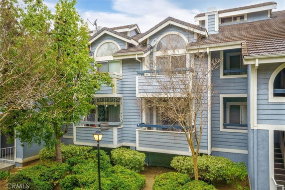 Front view of a multi-story blue house with arched windows and a small balcony.