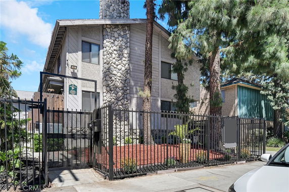 Front view of a two-story building with a stone chimney and metal fencing.