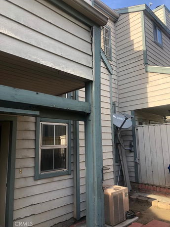 Partial view of a multi-story house exterior with wood siding and a window.
