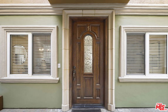 Front view of a house entrance with a wooden door and windows on either side.
