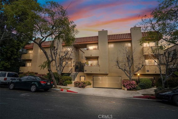 Front view of a multi-story apartment building with balconies and a gated entrance.