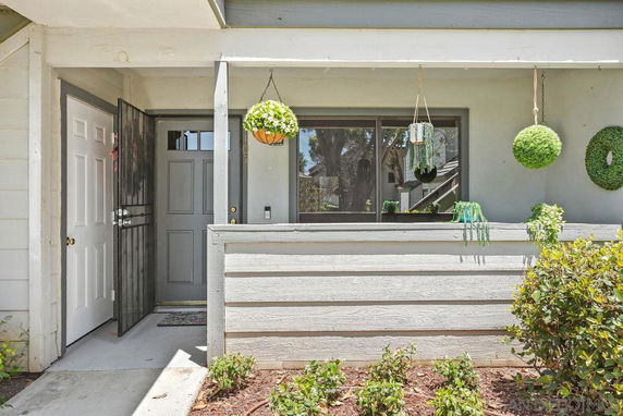 Front view of a house with a small porch and hanging plants.