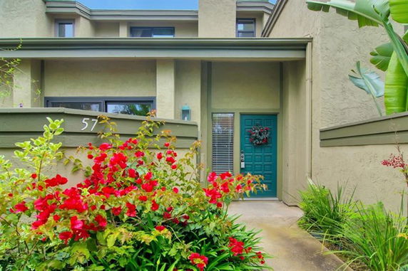 Front view of a house with a teal door and beige exterior walls.