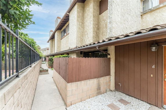 Front view of a two-story building with a walkway and wooden fence.