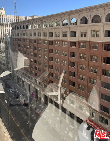 Elevated view of a large multi-story building with arched windows on the top floor.