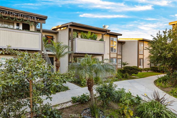 Front view of a multi-story apartment building with balconies and landscaped pathways.