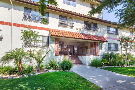 Front view of a multi-story residential building with a tiled roof and a central entryway.
