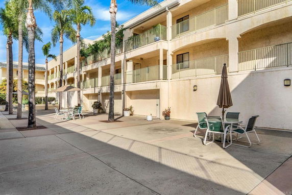 Courtyard view of a multi-story residential building with outdoor tables and umbrellas.