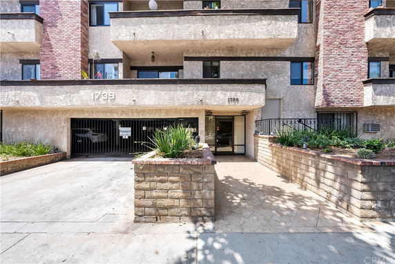 Front view of a multi-story building with balconies and a gated entrance.