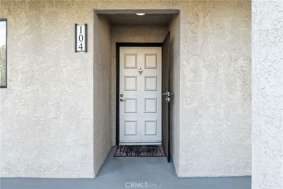 Front view of a building entrance with a white door and number 104.