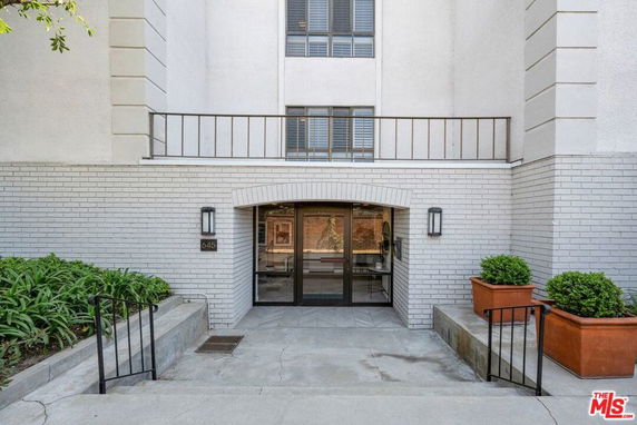 Front view of a building entrance with brick facade and glass doors.