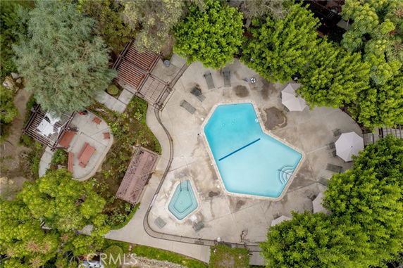 Aerial view of an outdoor swimming pool with surrounding deck chairs and umbrellas.