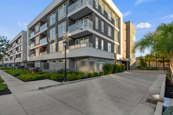 Front view of a modern multi-story apartment building with balconies.