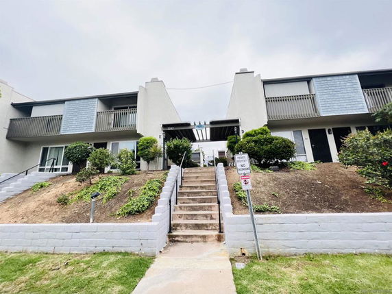 Front view of a two-story apartment building with stairs leading up.