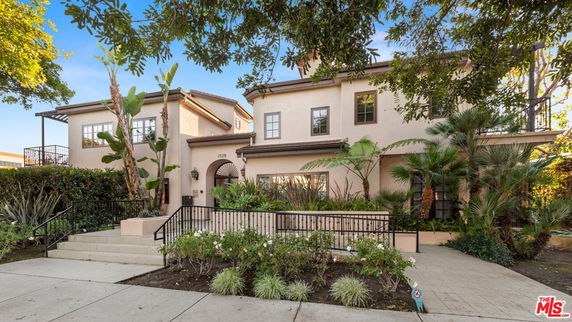 Front view of a two-story house with a decorative entrance and lush landscaping.